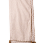A light beige linen throw blanket with brown tassels and decorative stitching along the edges