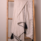 A linen cotton blend natural throw blanket with black tassels and a black geometric border pattern, draped over a wooden ladder