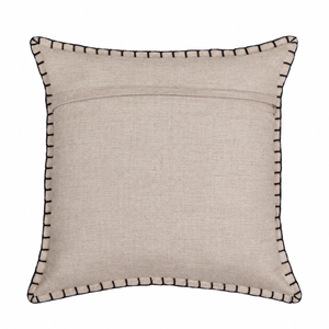 A back square beige linen throw pillow with black contrast stitching along the piped edges, shown against a plain white background.