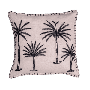 A square decorative throw pillow in a light blush pink fabric with black embroidered palm tree motifs and a black stitched border, shown against a plain white background.